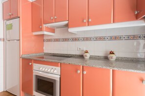A kitchen with pink cabinets, a white refrigerator, a stove, and a granite countertop. - Puerto Bahía House . (Tarifa)