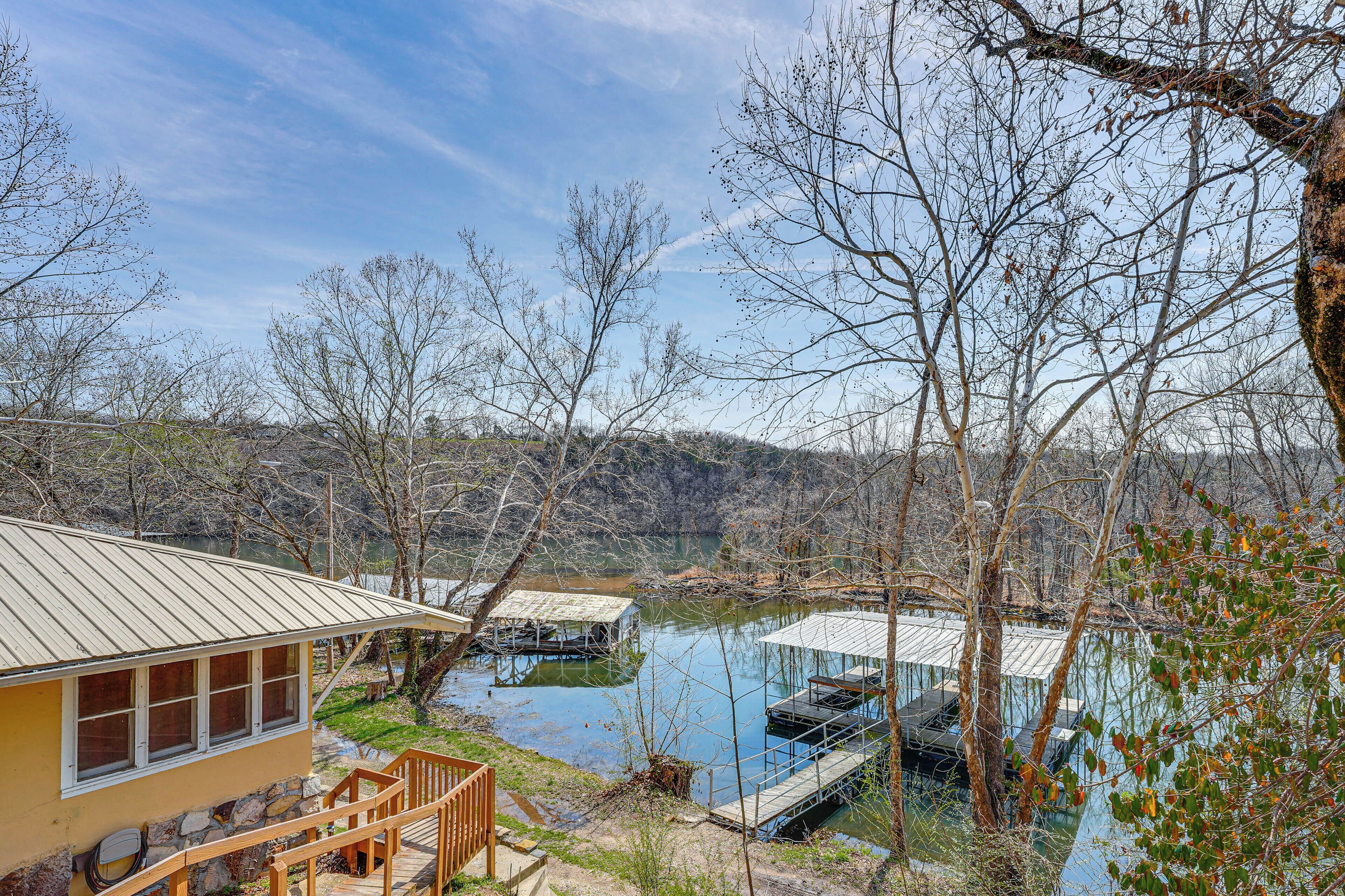 A lakeside cabin with a dock, a stone wall, and a wooden deck.