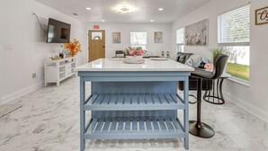 Una cocina moderna con encimera de mármol, una unidad de estanterías azul y una zona de bar con una silla.