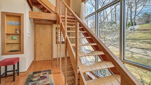 A wooden staircase with a view of the outdoors, a red bench, and a wall with a sign and a shelf. - Fun w/ Family! Lakefront Gem in Jamestown (Jamestown)