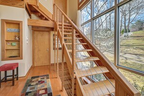 A wooden staircase with a view of the outdoors, a red bench, and a wall with a sign and a shelf. - Fun w/ Family! Lakefront Gem in Jamestown (Jamestown)
