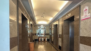 A corridor with marble walls, a trash bin, and an elevator. - The Maple Suite by Manhattan (Kuala Lumpur)