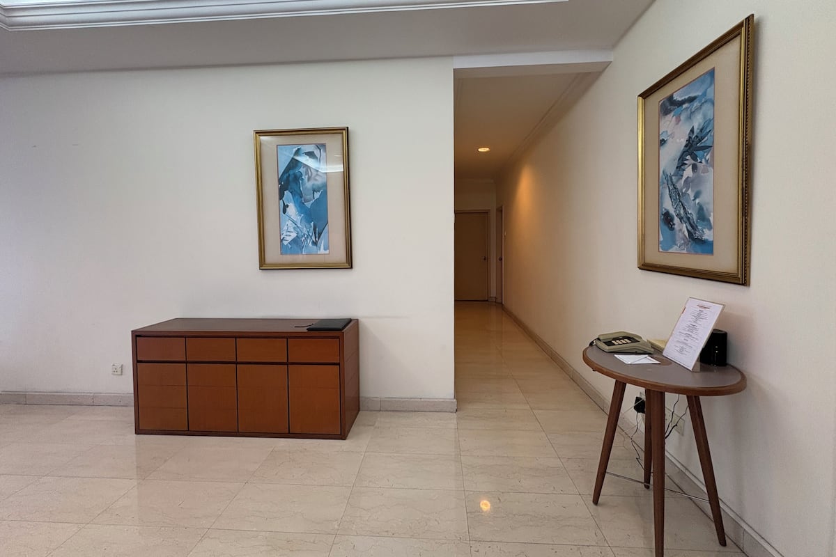 Un pasillo con un mostrador de recepción, un teléfono y dos cuadros abstractos enmarcados en las paredes.