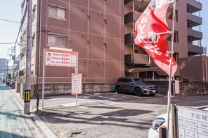 Monikerroksinen rakennus, jossa on pysäköintialue, pysäköintimaksuja ilmoittava kyltti ja lippu.