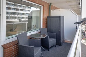 A balcony with wicker chairs, a small round table, and a view of a building with balconies. - WOMEN'S ROOM - Suite No. 7 - Women's room - Suite No. 7 (Sylt)