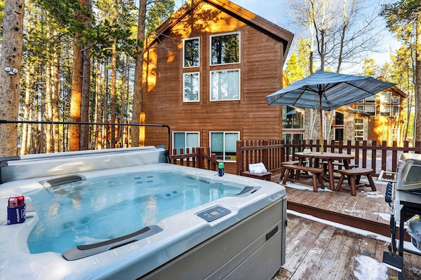 Back deck view featuring a relaxing hot tub and outdoor dining area.