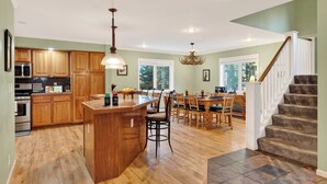 Une cuisine spacieuse avec des meubles en bois, un îlot central et un coin repas doté de chaises en bois.