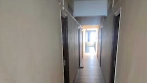 Un long couloir étroit, doté d’un sol carrelé et de portes des deux côtés.