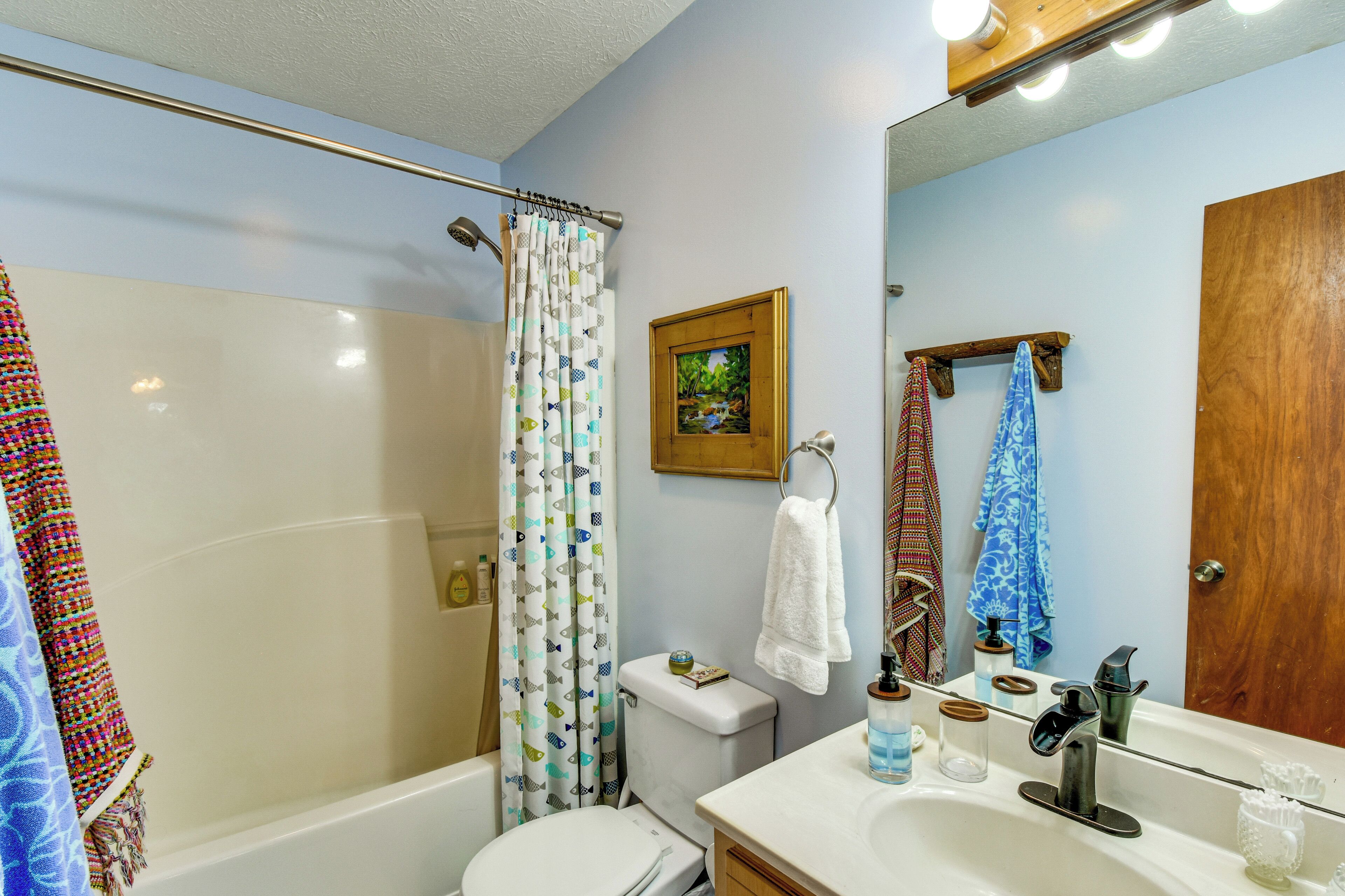 A bathroom with a bathtub, toilet, shower curtain, sink, mirror, and towels.