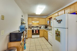 A kitchen with wooden cabinets, a white refrigerator, a stove, and a microwave.