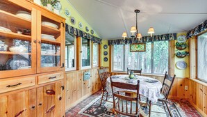 Une salle à manger en bois avec une table et des chaises, un buffet rempli de vaisselle et un tapis à motifs.