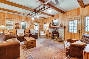 Ein Blockhaushaus-Interieur mit Kamin, Ledermöbeln, Holzwänden und einem großen Teppich.