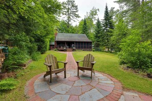 A house with a porch, two Adirondack chairs, and a stone pathway leading to the entrance. - All-Season Family Retreat w/ Dock on Loon Lake! (Chestertown)