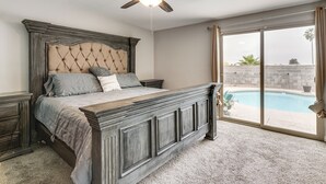 A bedroom with a large bed, a ceiling fan, and a view of a swimming pool. - Saguaro Retreat! Extended Stay in Tucson (Tucson)