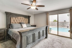 Ein Schlafzimmer mit einem großen Bett, einem Deckenventilator und Blick auf ein Schwimmbecken.