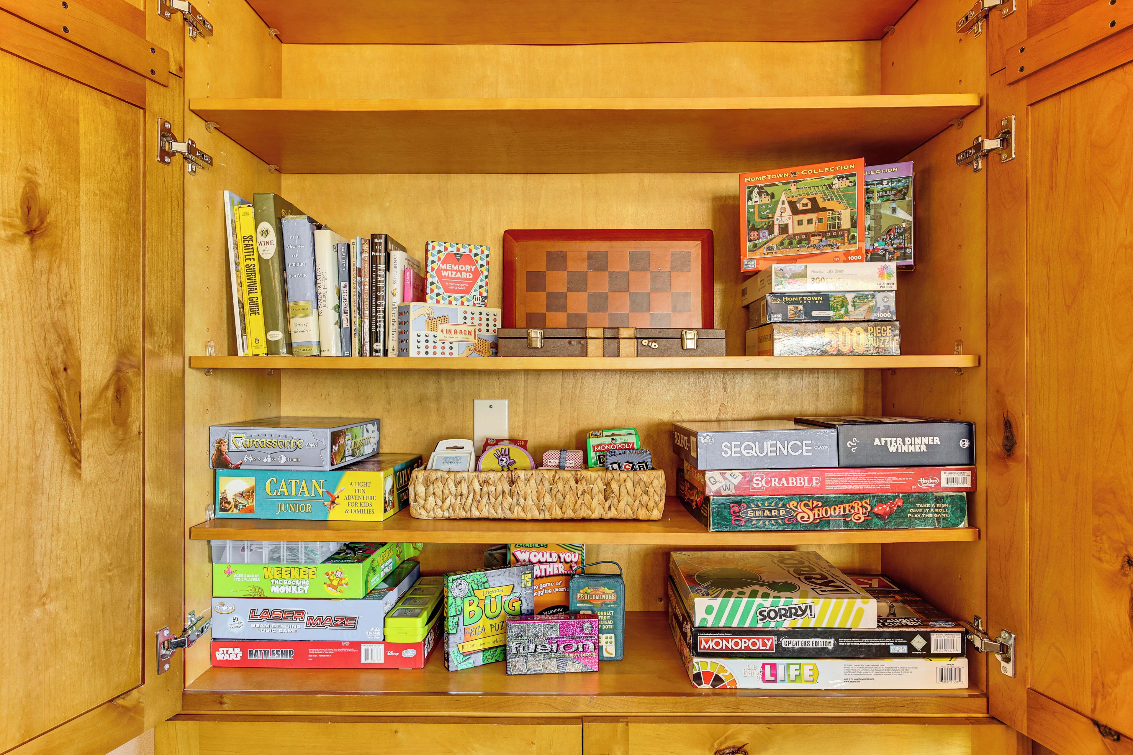 A wooden cabinet with shelves containing various board games and puzzles.