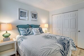 Ein Schlafzimmer mit einem Bett, zwei Wandlampen, einer Tür und zwei gerahmten Bildern.