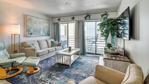 A living room with a sofa, a rocking chair, a coffee table, and a large window with curtains. - Walk to Pool & Beach! 3rd-Floor Murrells Inlet Gem (Murrells Inlet)