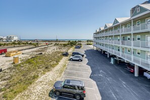 Un hotel frente a la playa con varios pisos, estacionamiento y vista al océano.