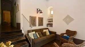 A living room with a sofa, a wicker chair, a staircase, and a bookshelf. - Villa in Chiaramonte Gulfi with 3 bedrooms sleeps 8 (Chiaramonte Gulfi)