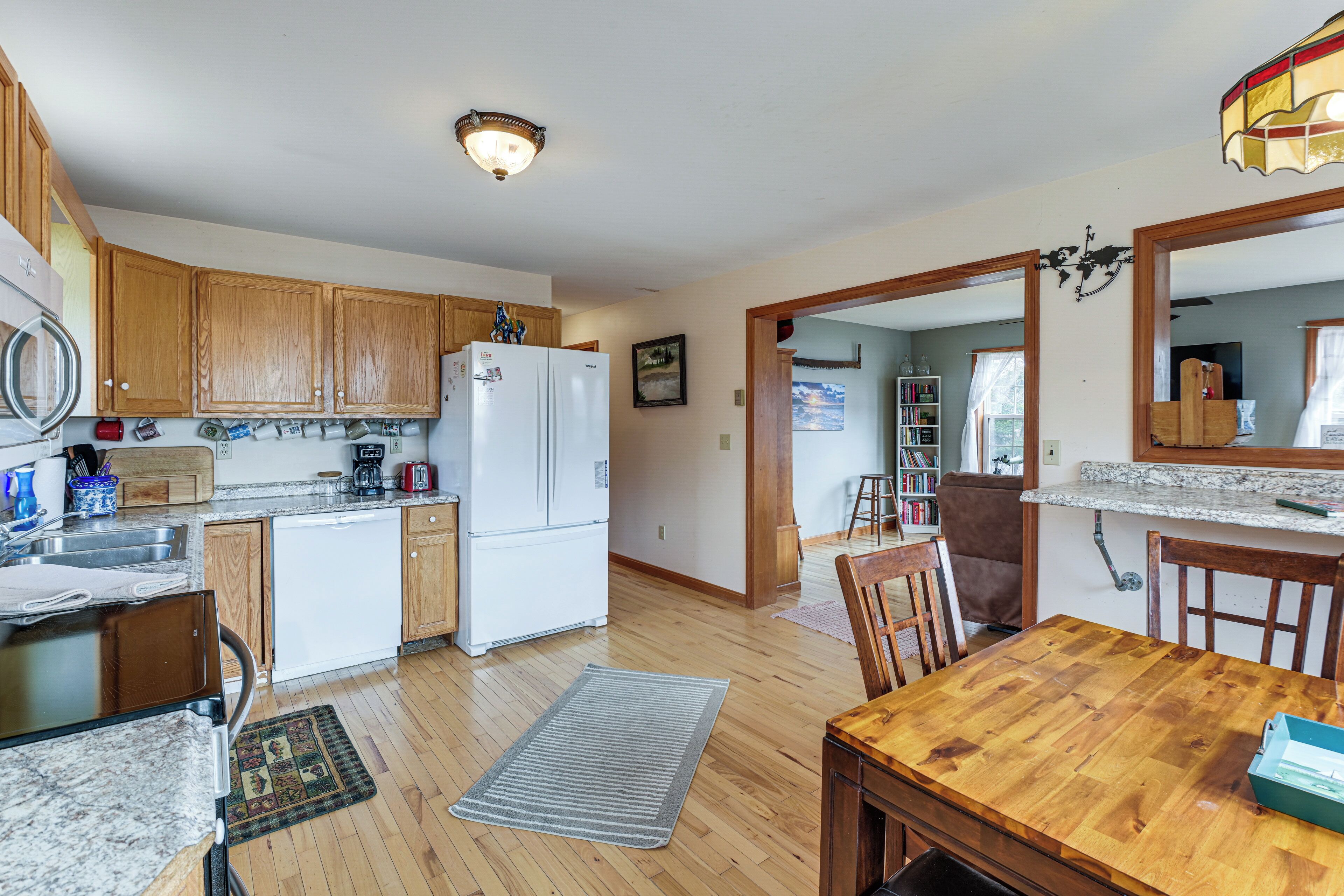 A kitchen with wooden cabinets, a refrigerator, a dining table, and a rug.