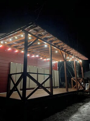Un espace extérieur abrité doté d’une structure en bois, d’une porte de garage et de guirlandes lumineuses.