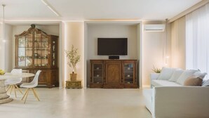Ein Wohnzimmer mit Essbereich, Fernseher und einer Couch.