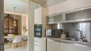 Eine moderne Küche mit Mikrowelle, Backofen und Spüle. Ein Essbereich mit Tisch und Stühlen ist ebenfalls vorhanden.