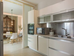 A modern kitchen with a microwave, oven, and sink. There is a dining area with a table and chairs. - Villa / Independent home in Lido Di Camaiore with 4 bedrooms sleeps 8 (Lido Di Camaiore)