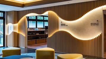 A modern interior with a self-cleaning room sign, a reception desk, and a seating area with ottomans.