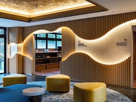 A modern interior with a self-cleaning room sign, a reception desk, and a seating area with ottomans.