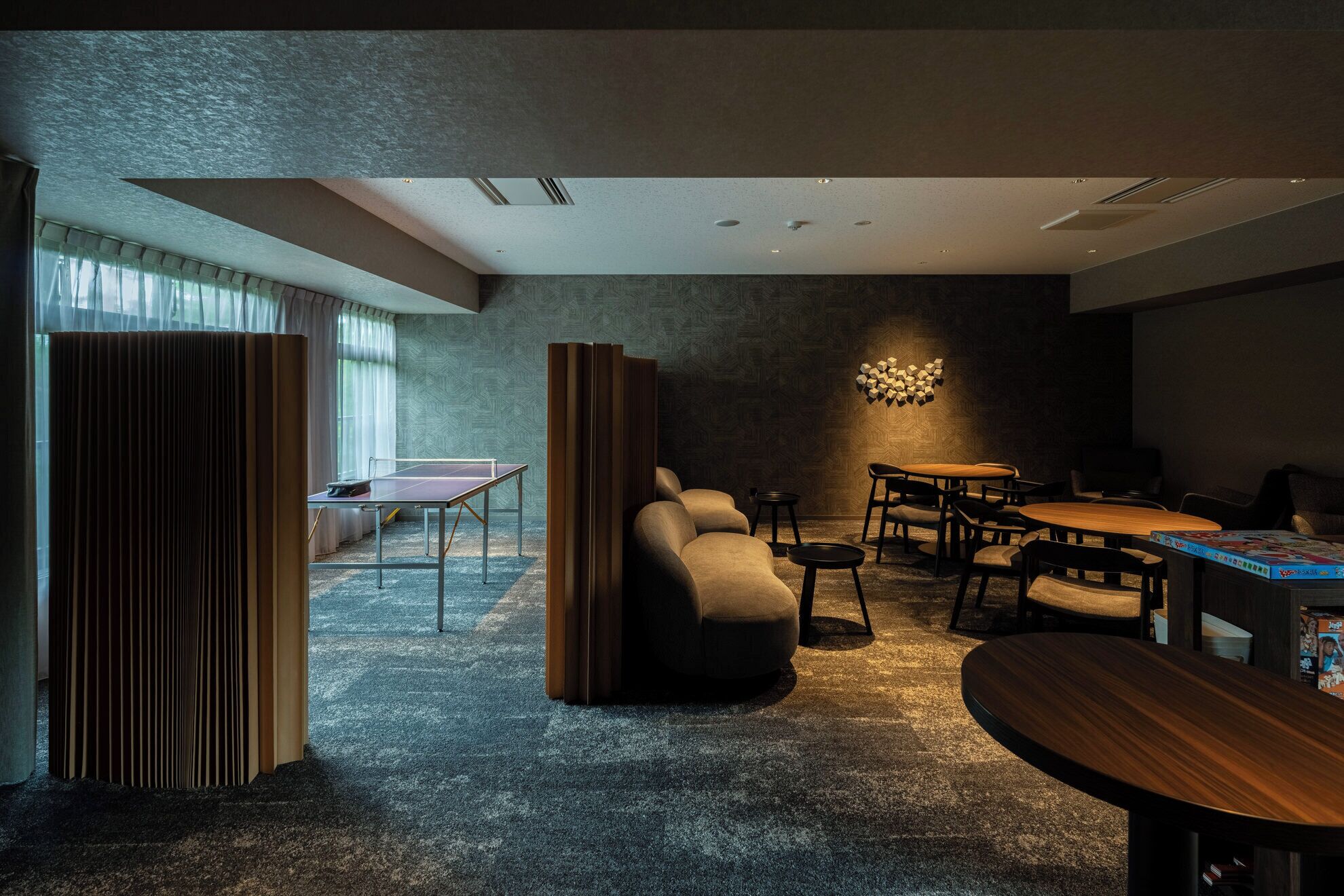 A modern room with a ping pong table, sofas, and a dining area.