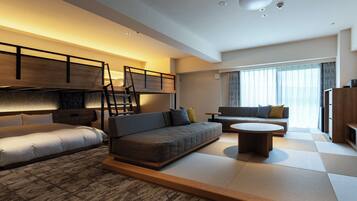 A modern hotel room with a bunk bed, sofa, and a small round table.