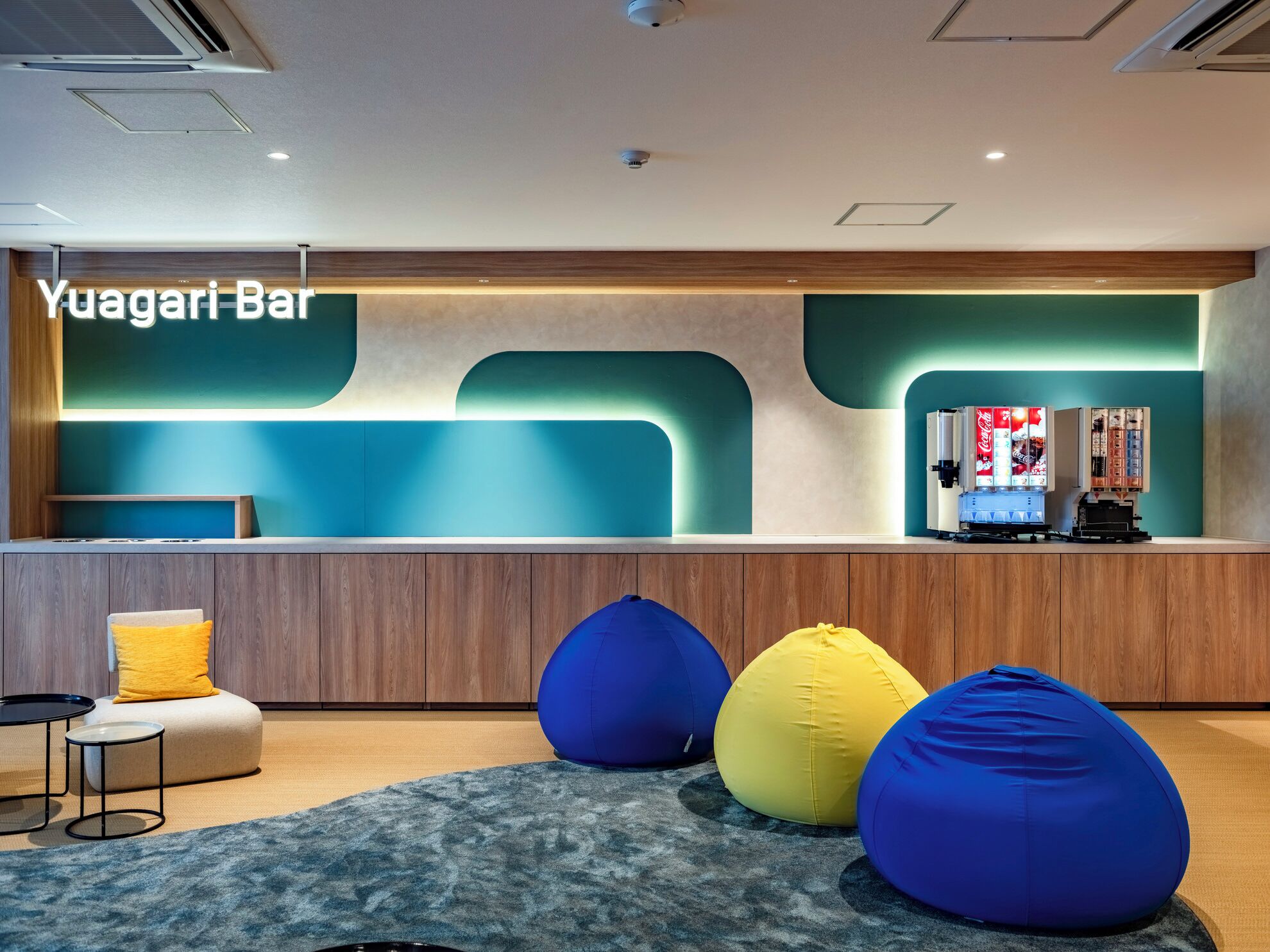 A modern bar area with a reception desk, seating, and vending machines.