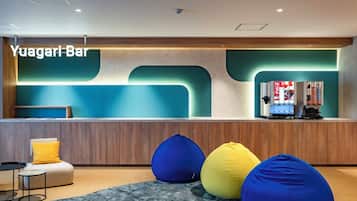 A modern bar area with a reception desk, seating, and vending machines.