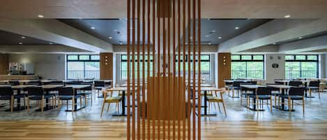 A spacious indoor area with multiple tables and chairs, large windows, and a central wooden partition.