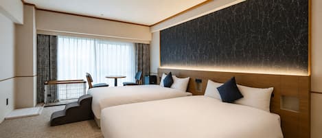 A hotel room with two beds, a desk, and a view of the city.