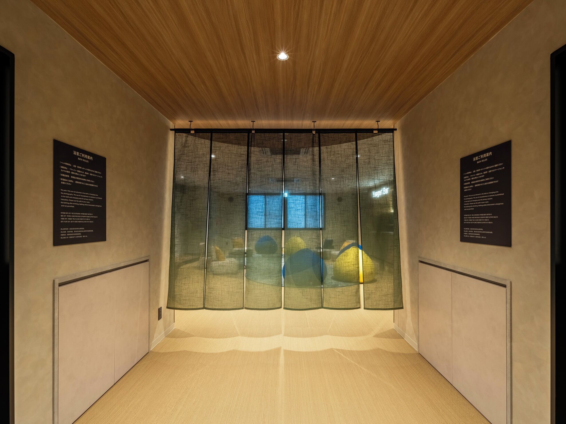 A room with a wooden ceiling, a large window with a view, and two informational plaques on the walls.