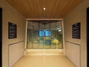A room with a wooden ceiling, a large window with a view, and two informational plaques on the walls. - B/C HOTEL KUSATSU (Kusatsu)