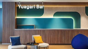 A modern bar area with a sign reading 'Yuagari Bar,' a seating area with a sofa and chairs, and a round table.