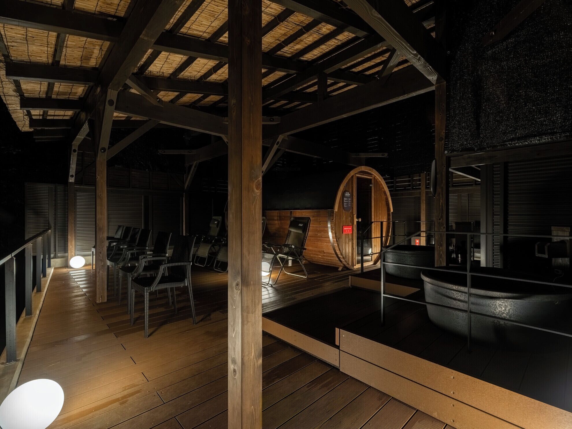 Sauna, jossa on puupalkit, puinen penkki ja lasiseinäinen tila.