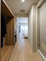 A hallway with a wooden wardrobe, a bed, and a bathroom with a shower.