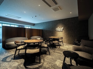A modern interior with a seating area, tables, and a unique wall light fixture. - B/C HOTEL KUSATSU (Kusatsu)