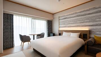 A modern hotel room with a large bed, a desk, and a sofa.