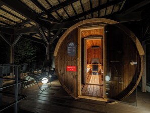 Una cabana de fusta amb una porta circular, un espai interior petit amb una banca i una llar de foc, i un senyal que indica l'ús de tovalloles.