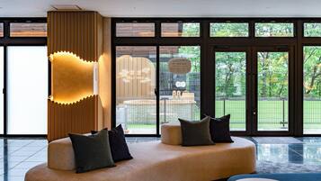 Un moderno vestíbulo de hotel con una zona de estar curva, ventanas amplias y vistas al exterior.