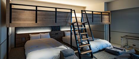 Una habitación de hotel moderna con literas, una escalera, un sofá y una pequeña mesa.