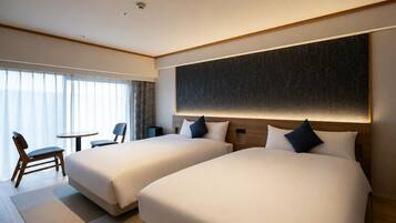 A hotel room with two beds, a desk, and a chair.