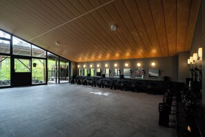 A spacious room with a wooden ceiling, large windows, and a bar area with stools.