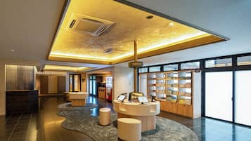 Un hall d’hôtel moderne doté d’un comptoir d’enregistrement, d’un espace salon et d’une grande fenêtre offrant une vue sur l’extérieur.